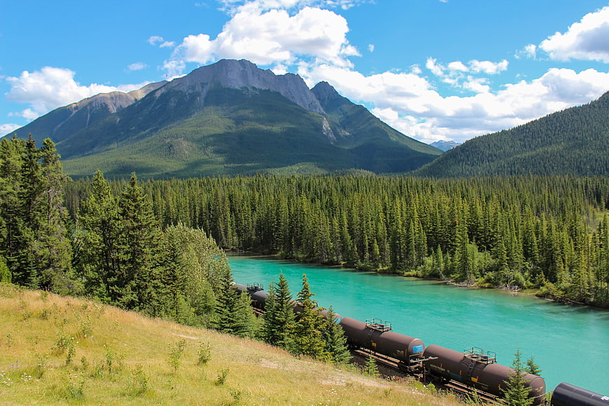 Freight train crossing turquoise river in mountain valley