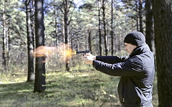 Man Shooting Pistol With Muzzle Flash In Pine Forest