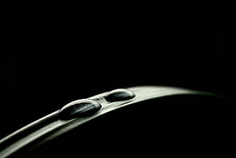 Macro water droplets on a curved leaf edge against black background