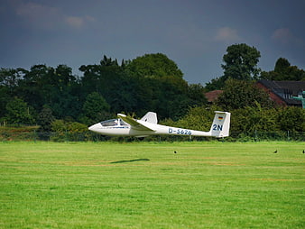 White glider aircraft parked on grassy airfield