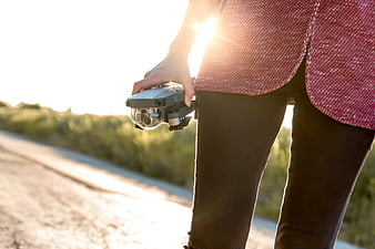 Woman holding drone controller on sunny road