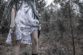 Woman holding cleaver in desaturated forest horror concept