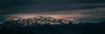 Dramatic Snow-Capped Mountain Range Under Dark Stormy Sky