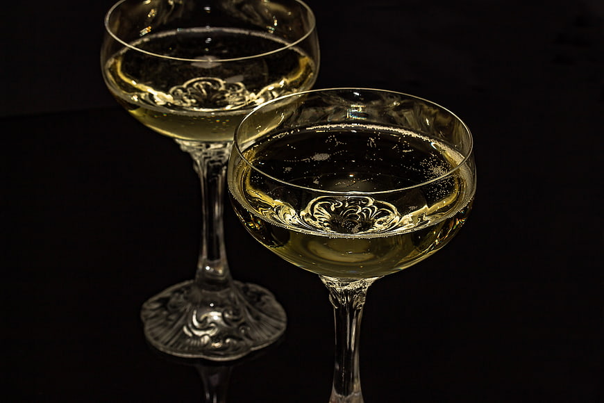 Two elegant champagne glasses with sparkling wine on black background