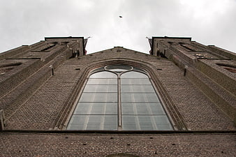 Low angle view of brick church facade with large arched window