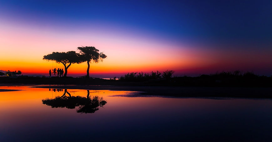 Silhouette of Trees and People at Sunset with Water Reflection