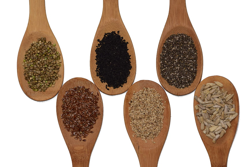 Assorted Seeds on Wooden Spoons Isolated on White Background