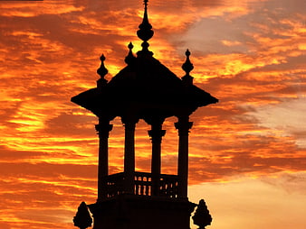 Silhouette of ornate gazebo against vibrant orange sunset sky