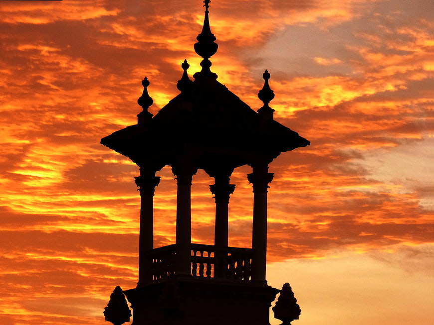 Silhouette of ornate gazebo against vibrant orange sunset sky