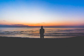 Silhouette of Person Standing on Beach at Sunset