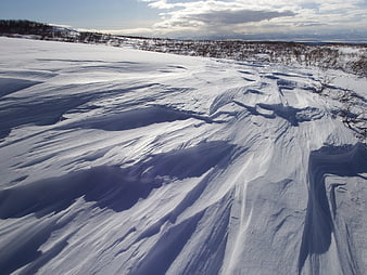 Vast Snowy Landscape with Wind-Scoured Drifts and Distant Mountains