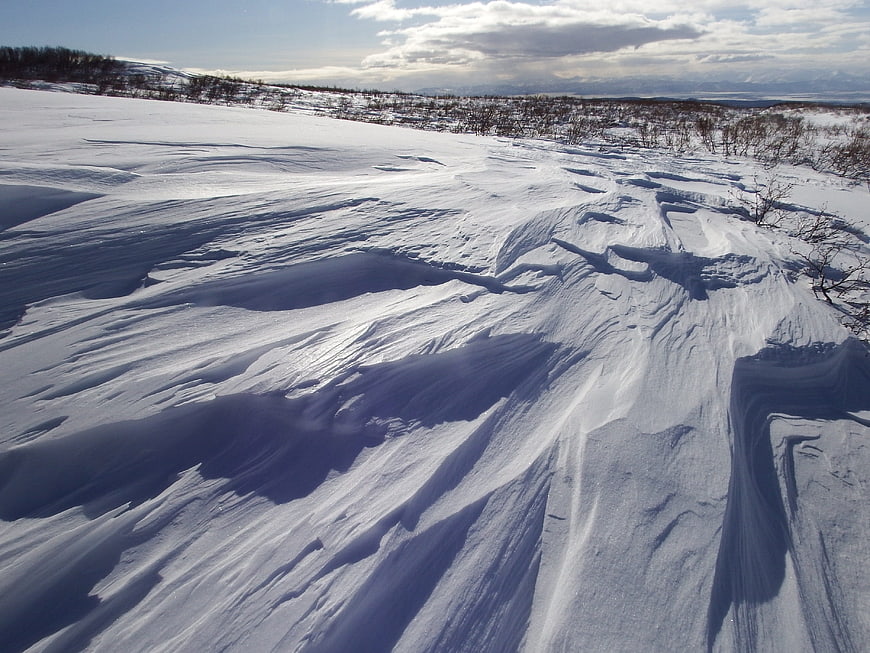 Vast Snowy Landscape with Wind-Scoured Drifts and Distant Mountains
