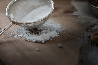 Metal sieve with powdered sugar on rustic wooden table