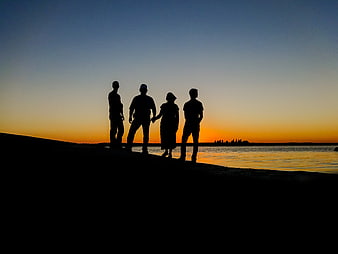 Silhouette of Four Friends Standing on Beach at Sunset