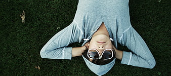 Woman in Hoodie and Sunglasses Lying on Grass