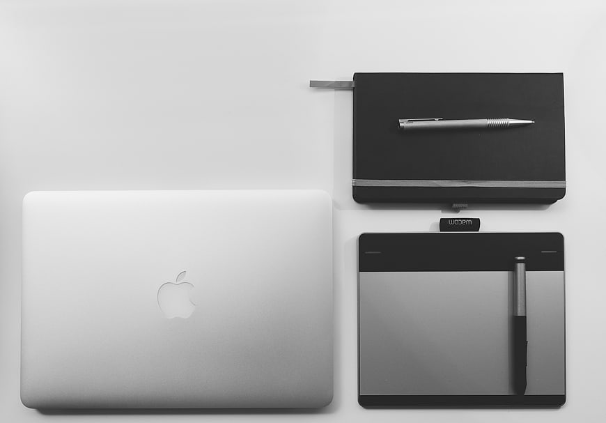 Minimalist flat lay of MacBook, Wacom tablet, and notebook