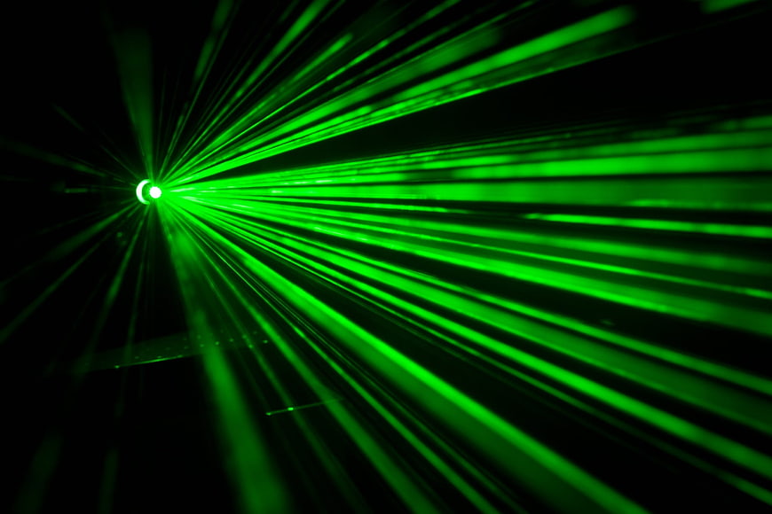 Vibrant green laser beams radiating from a central point in the dark