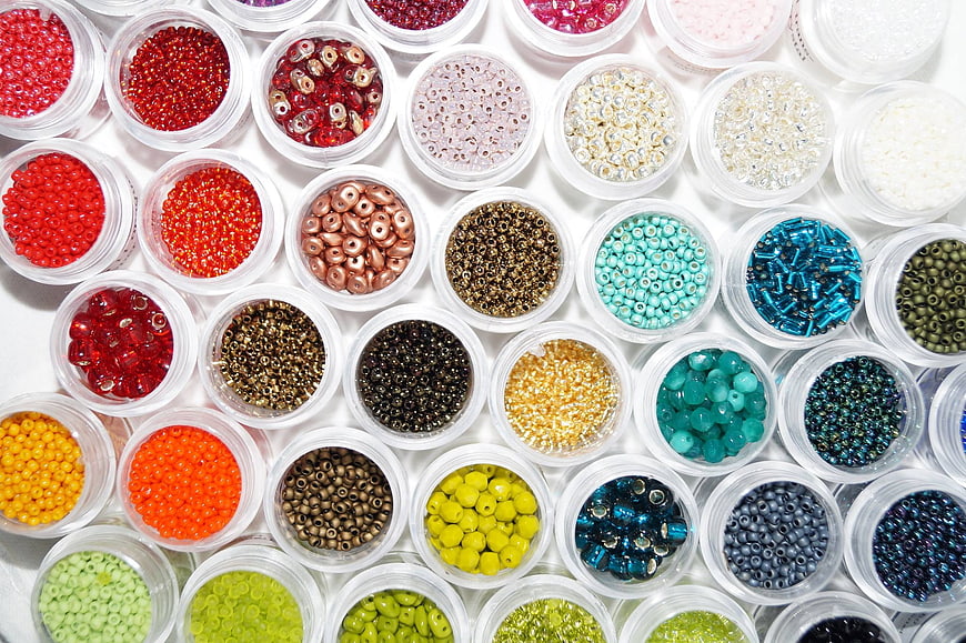 Colorful Beads In Plastic Containers On White Background