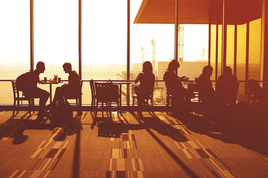 Silhouetted Travelers Waiting in Airport Lounge at Sunset
