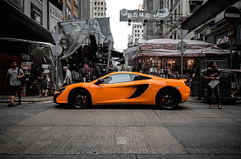 Orange McLaren sports car parked on busy Hong Kong street