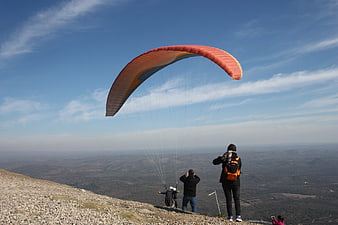 Paraglider Launching from Mountain Cliff with Spectators