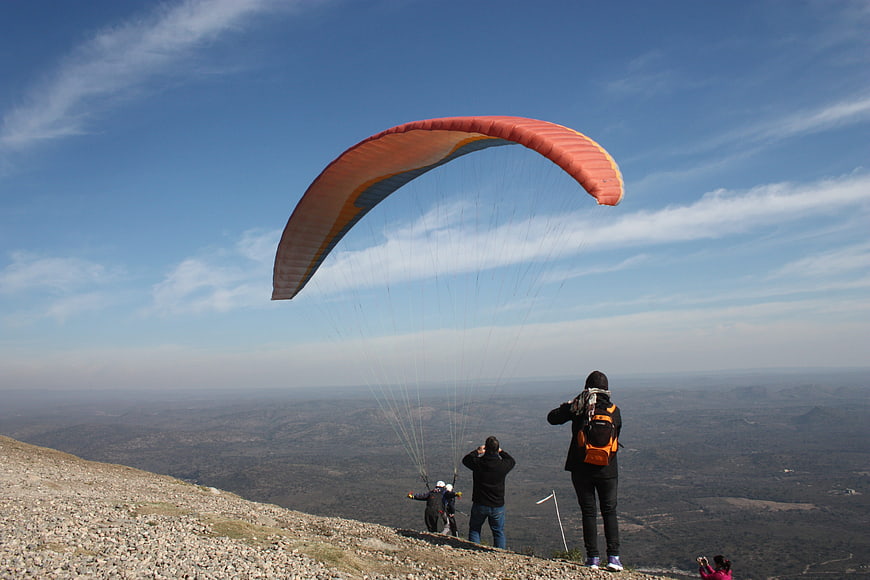 Paraglider Launching from Mountain Cliff with Spectators