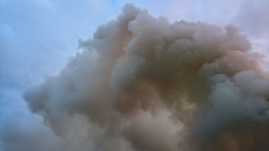 Dramatic Smoke Plume Rising Against Blue Sky