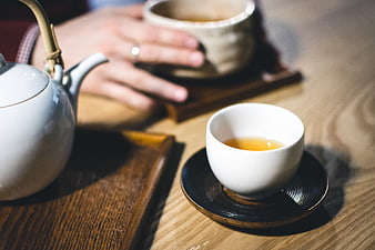 Close-up of hands holding tea cup on wooden table