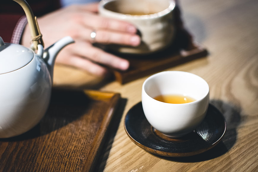 Close-up of hands holding tea cup on wooden table