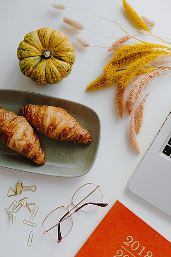 Autumn workspace flat lay with croissants and pumpkin
