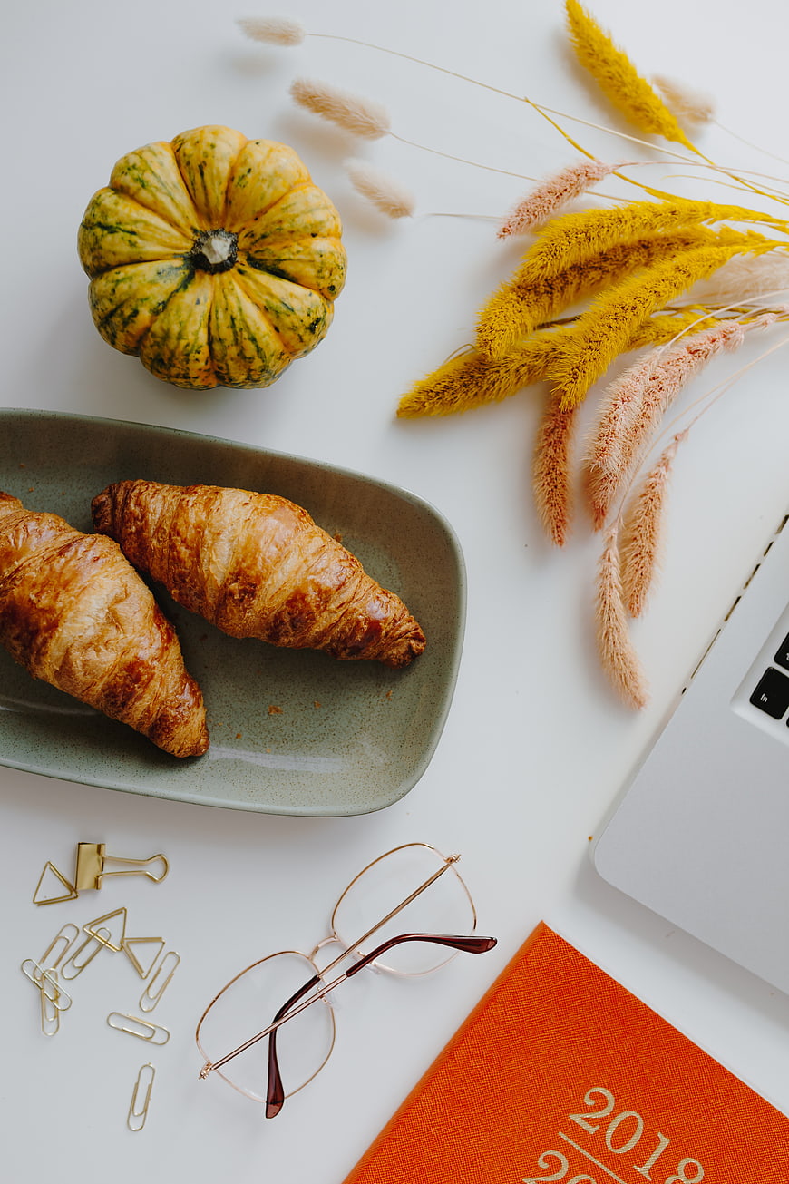 Autumn workspace flat lay with croissants and pumpkin