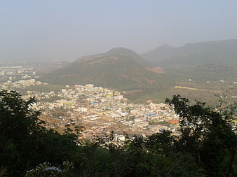 Hazy panoramic view of city nestled in valley with mountains