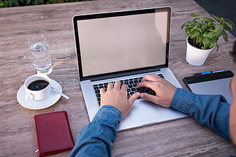 Freelancer working on laptop at wooden table with coffee