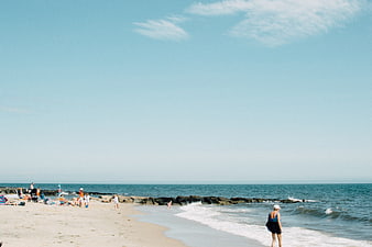 Sunny Beach Scene with People Relaxing and Walking by the Ocean