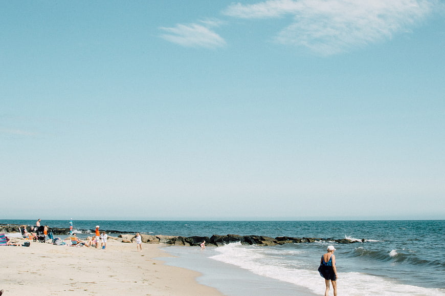Sunny Beach Scene with People Relaxing and Walking by the Ocean