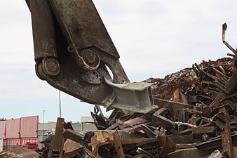 Heavy machinery shears sorting scrap metal at recycling facility