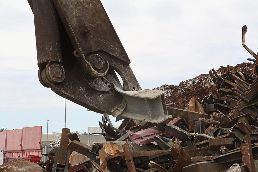 Heavy machinery shears sorting scrap metal at recycling facility