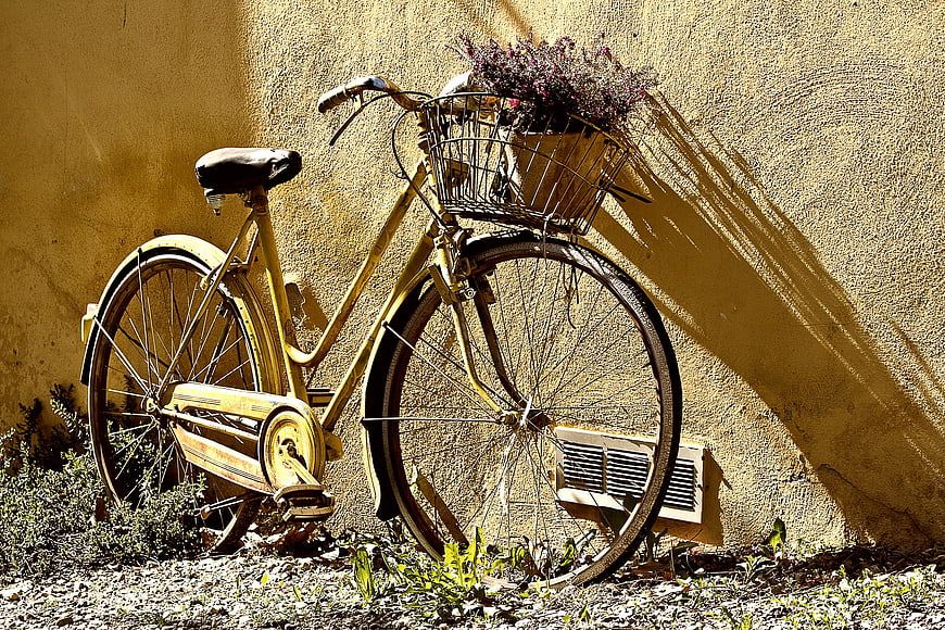 Vintage yellow bicycle with flowers against textured wall