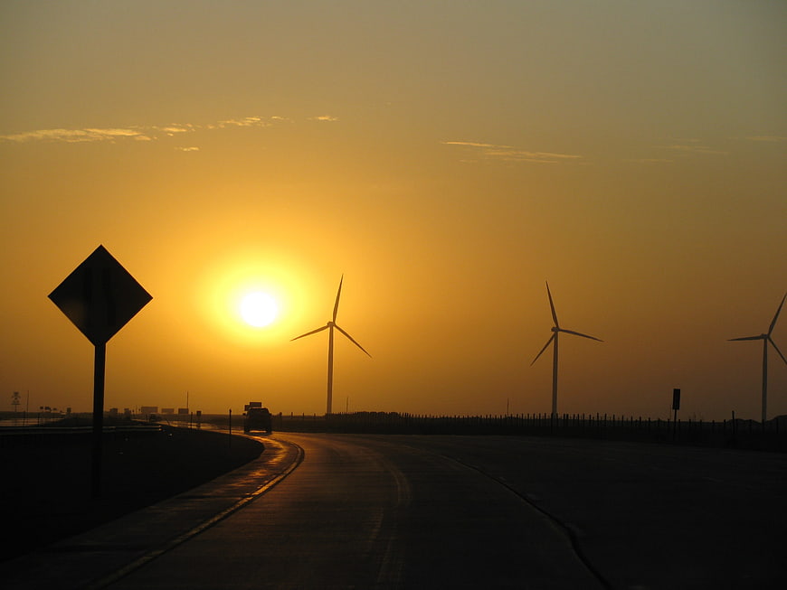 Silhouette of wind turbines on highway at golden sunset