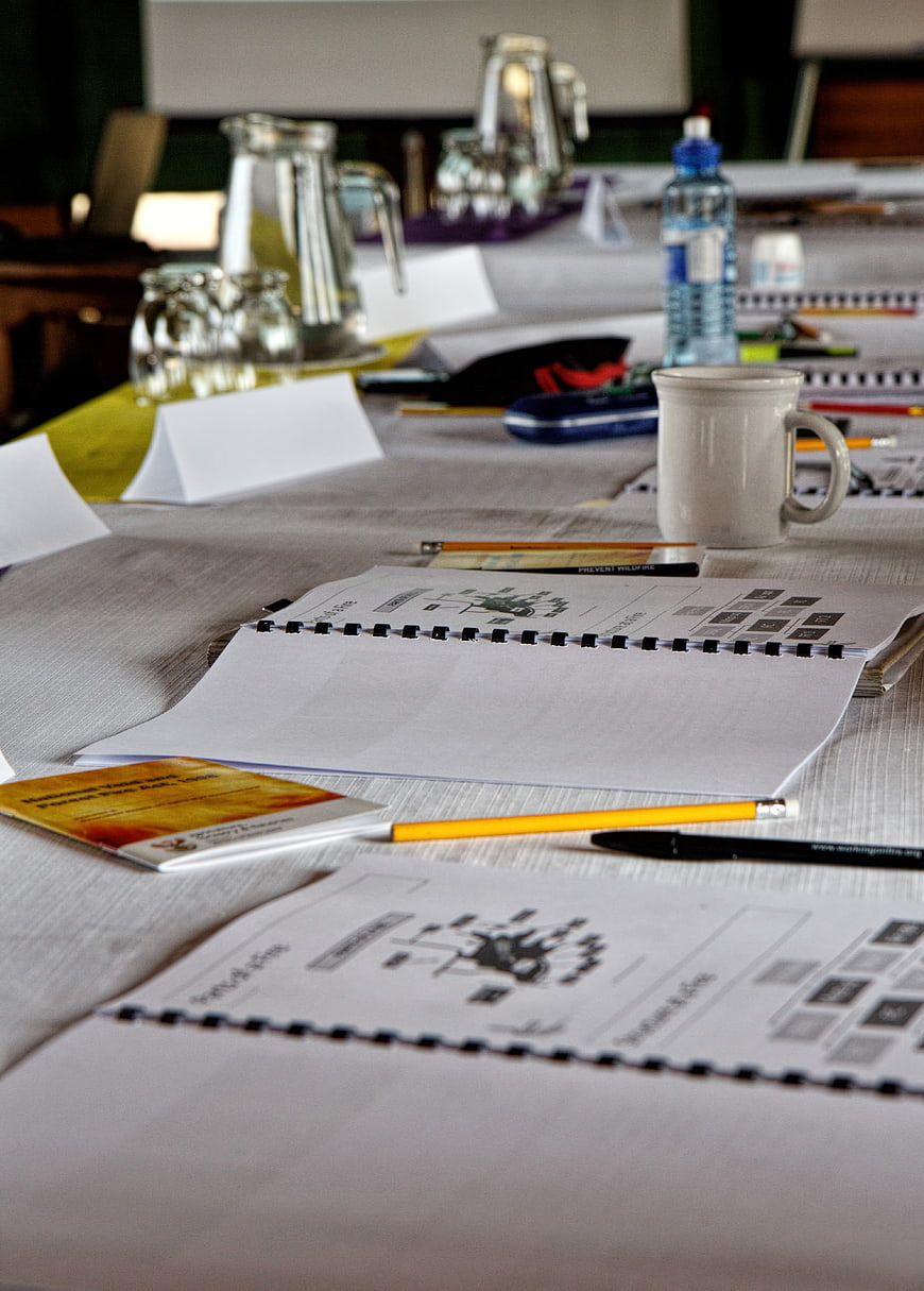 Conference table setup with notebooks, pencils, and water bottles