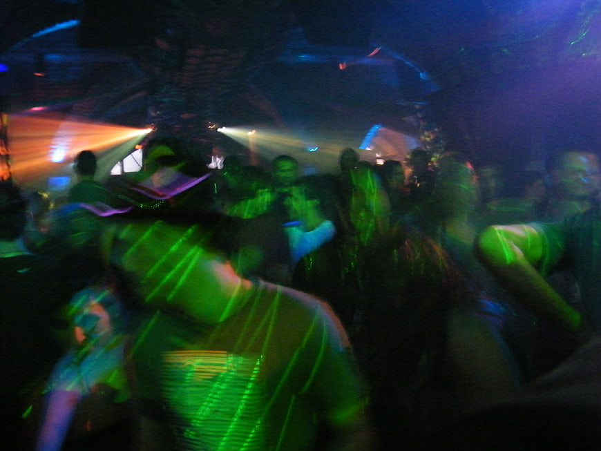 Blurred Crowd Dancing In Green And Blue Neon Club Lights