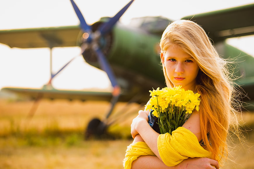 Portrait of Blonde Girl with Yellow Flowers and Vintage Plane