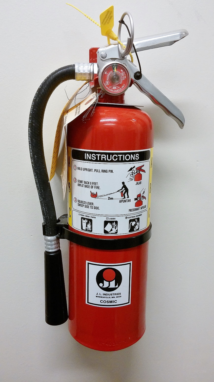 Red Fire Extinguisher With Instruction Label On White Wall