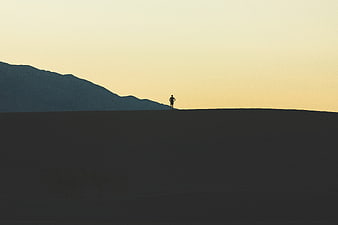 Silhouette of Man Standing on Hill Against Sunset Sky