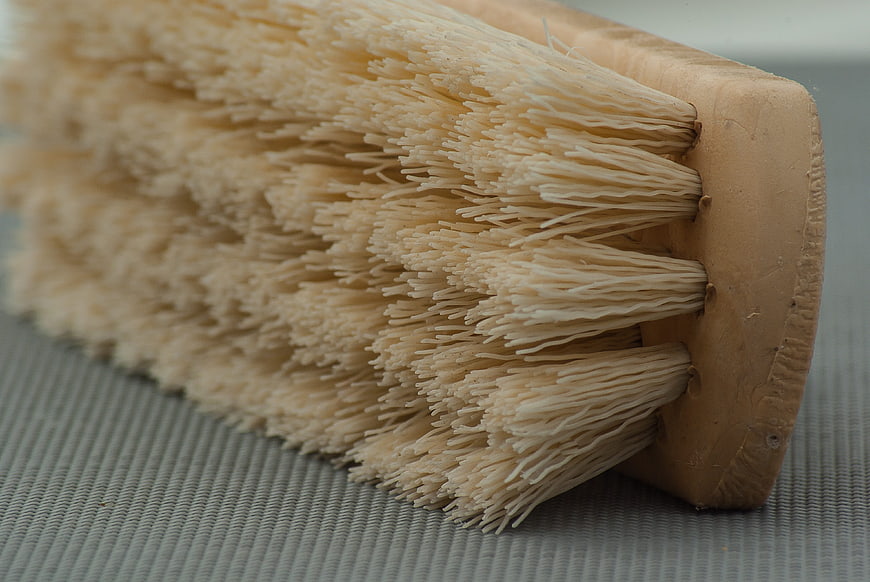 Close-up of natural bristle cleaning brush on textured gray surface