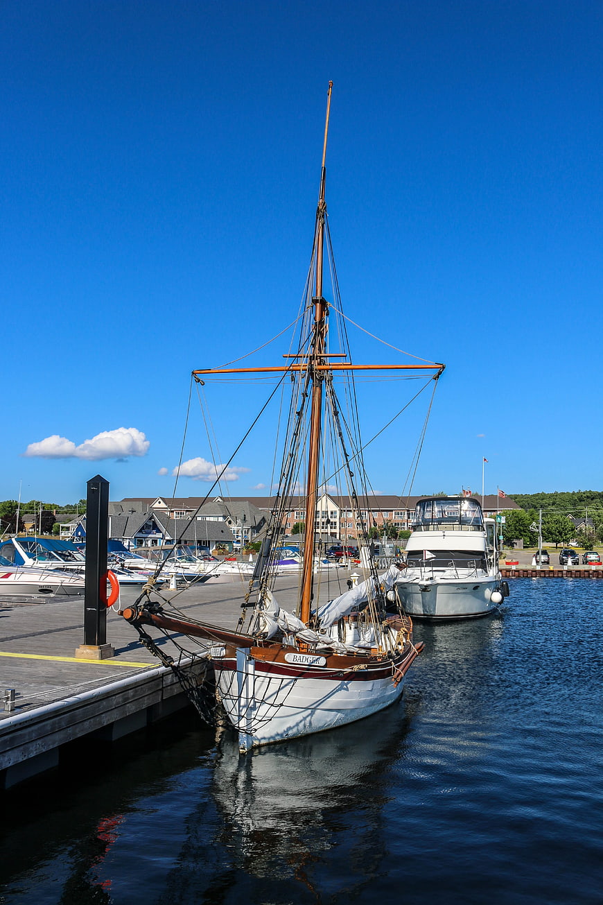 Classic wooden sailboat docked at sunny marina