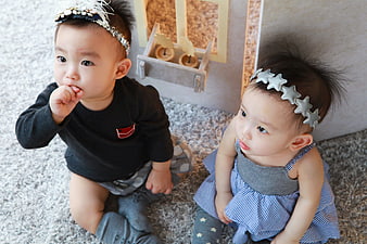 Adorable twin babies sitting on a fluffy rug with headbands