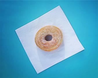 Top view of sugar donut on white napkin blue background