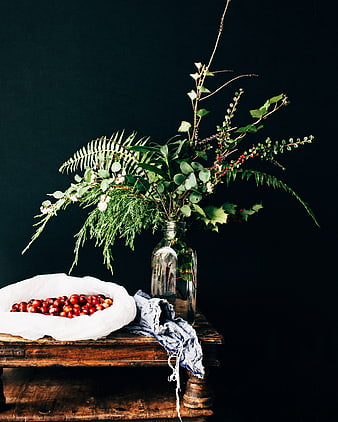 Rustic still life with greenery, berries, and vintage bottle