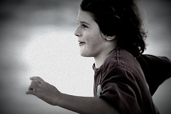 Profile of a smiling boy running outdoors in black and white